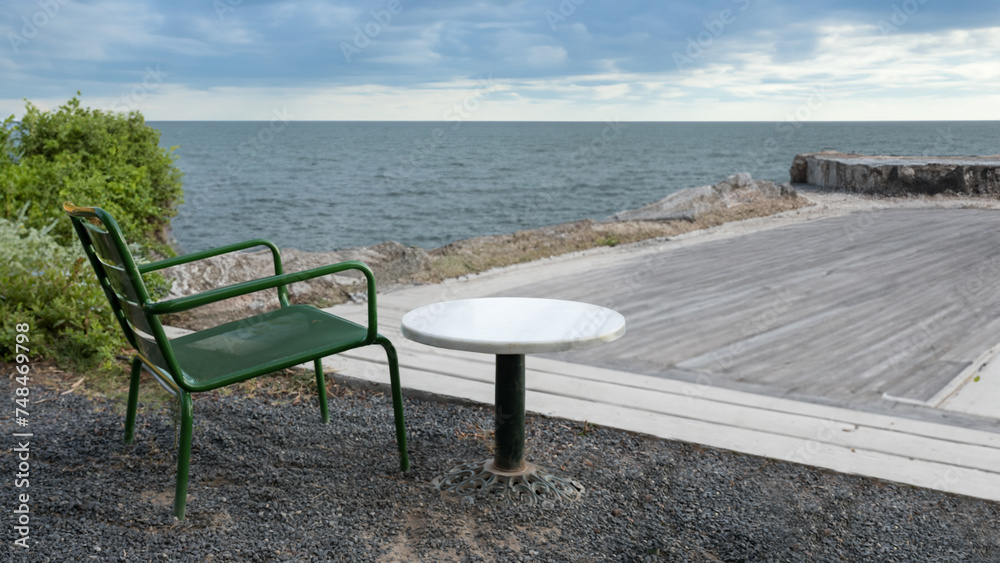 Green chair and table on the beach with the sea in the background