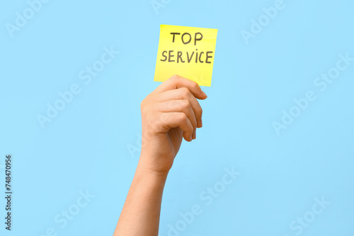 Woman holding paper with text TOP SERVICE on blue background. Customer experience concept