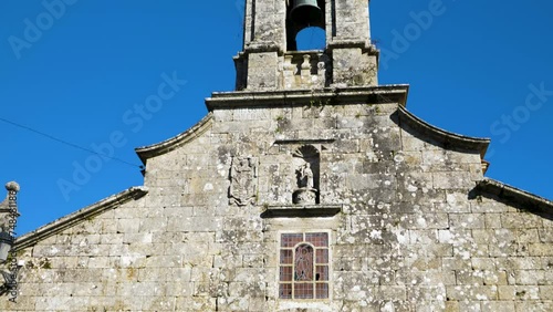 Tilt up establish of entracne to San Xoan de Rio church and bell tower against blue sky photo