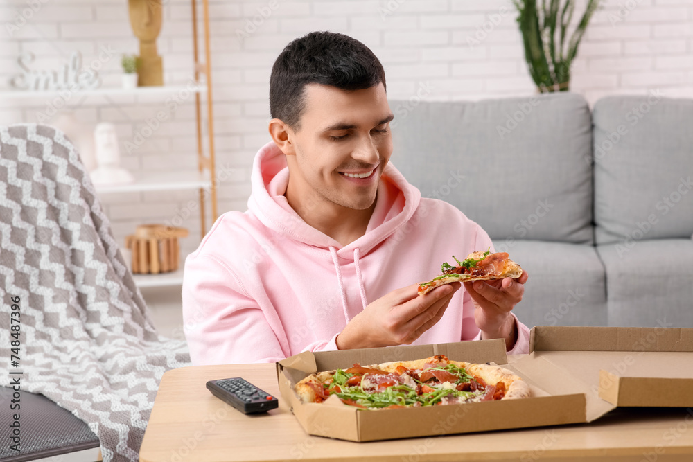 Young man with piece of tasty pizza at home Young man with piece of tasty pizza at home