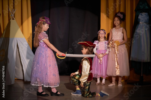 Side view portrait of young girl on stage in school play production acting as warrior princess holding sword and defeating pirate copy space photo