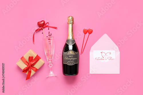 Bottle of champagne with glass, gift box and decor on pink background. Valentine's Day celebration