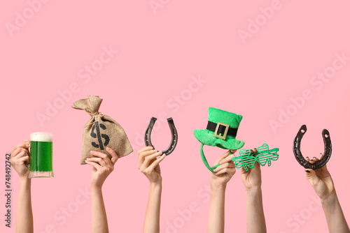 Female hands holding beer and party decor for St. Patrick's Day celebration on pink background photo
