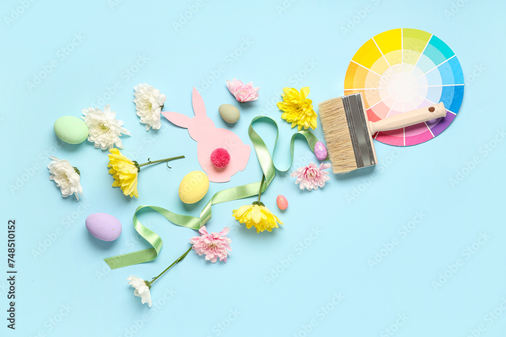Composition with paint brush, palette samples, Easter eggs and flowers on color background