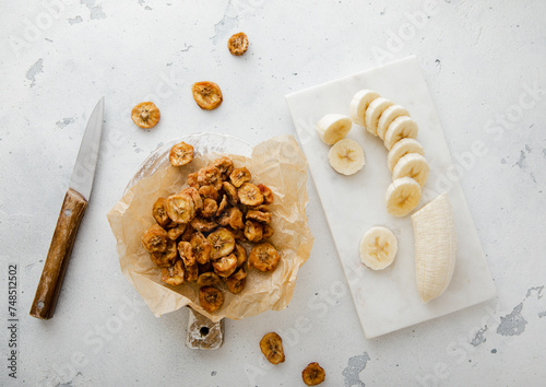 Dried round banana slices with fresh peeled banana and knife. © DenisMArt