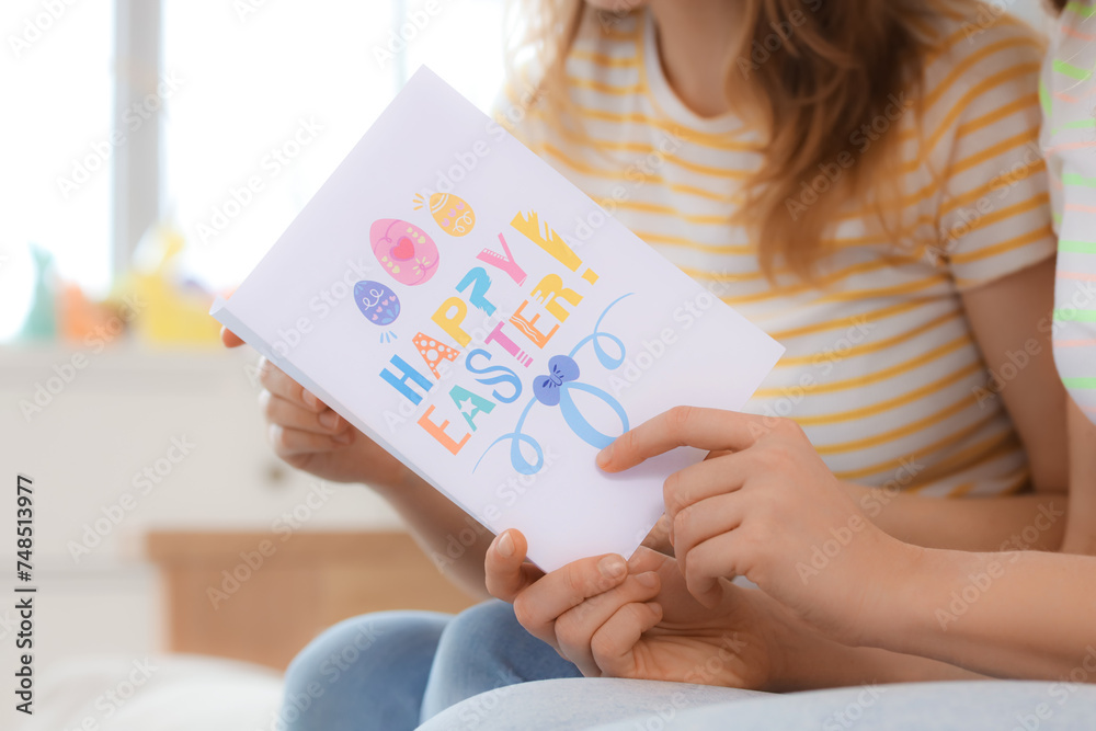 Young women holding festive postcard with text HAPPY EASTER at home Young women holding festive postcard with text HAPPY EASTER at home