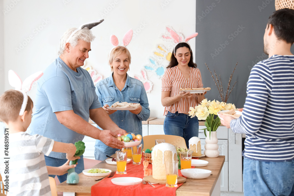 Happy family setting table for Easter dinner in kitchen