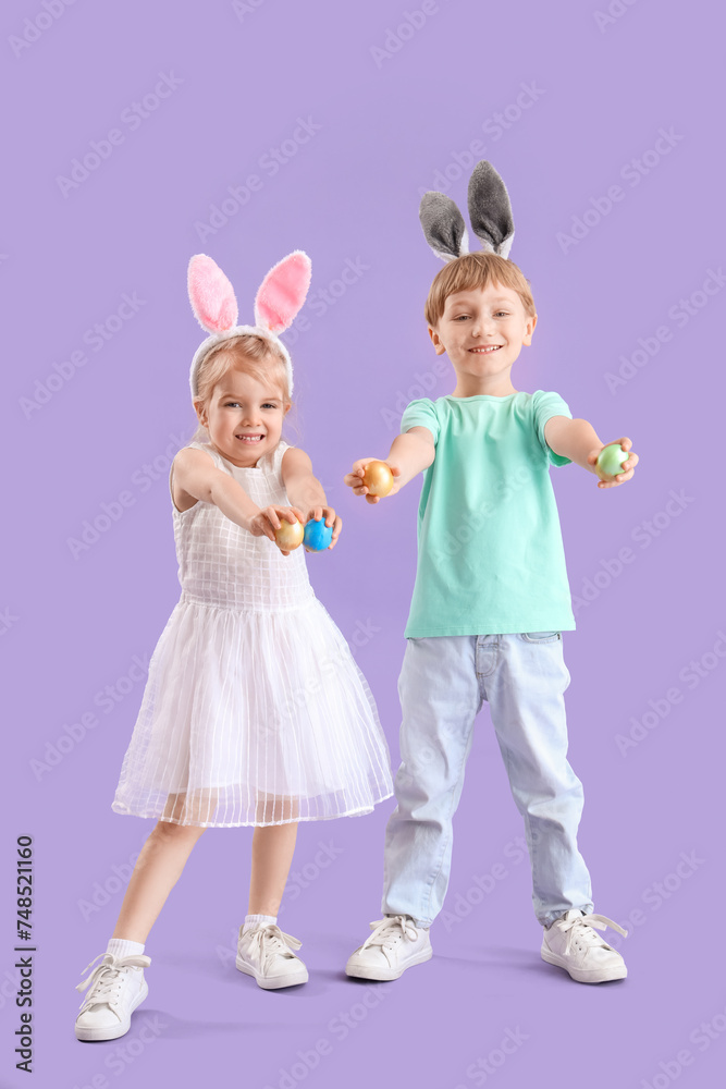 Little children in bunny ears with Easter eggs on lilac background