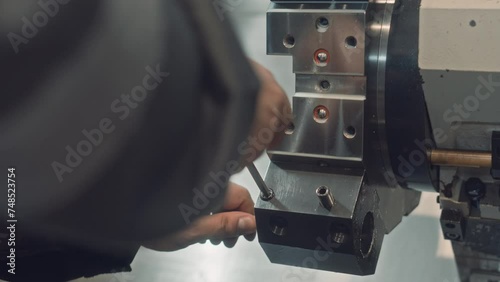 Unrecognizable mechanic at factory using allen wrench to tighten hexagonal bolts on metal equipment photo