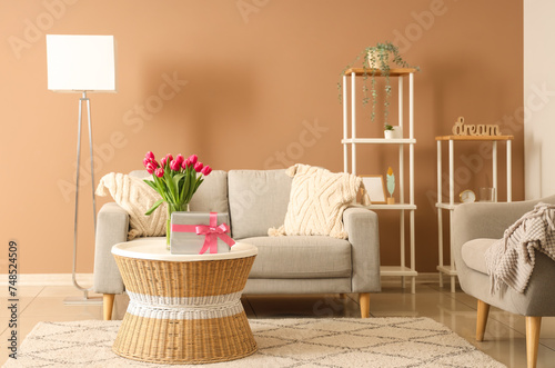 Interior of modern living room with flowers and gift box on coffee table in living room photo