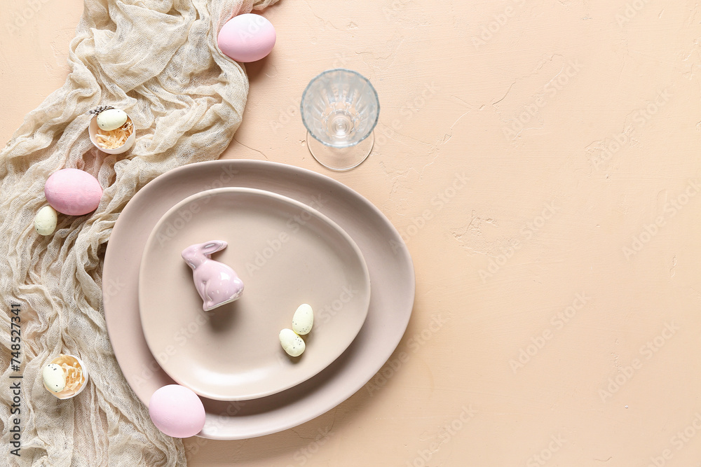 Table setting for Easter celebration with painted eggs and cloth on beige background