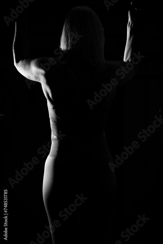 Blonde woman in her mid-fifties training in the gym, photo with flash against a black background. © RD-Fotografie