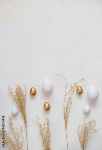 Beautiful Easter golden eggs and tree branches on white background with space for text