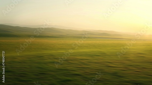 A vast grassland with rolling hills in the background under a golden light