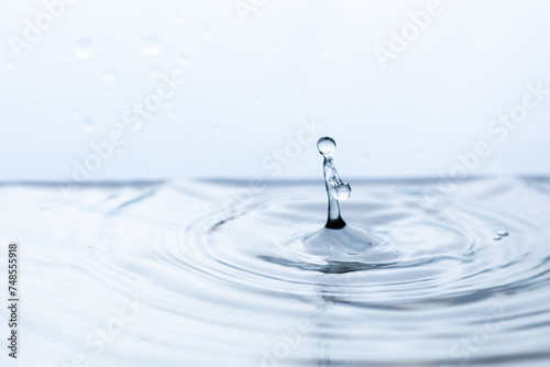 An ethereal splash frozen in time as a droplet dances upon pristine water, resembling a human figure in its reflection
