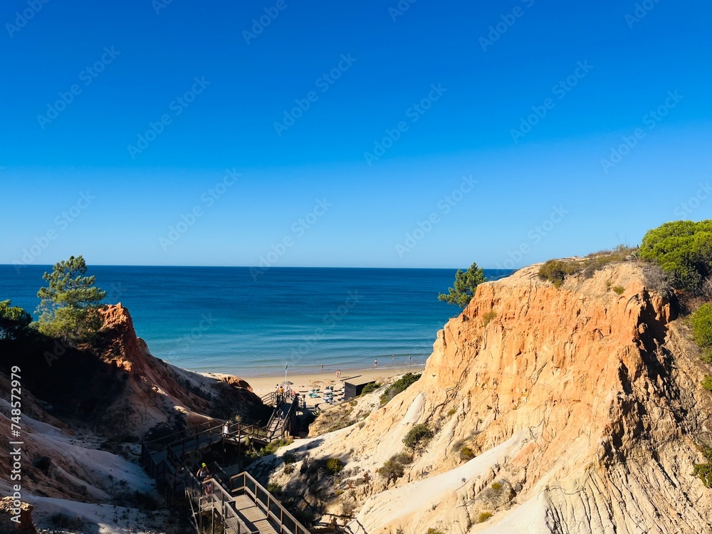 Sandstone rocky coast, blue ocean horizon, clear sky, ocean bay