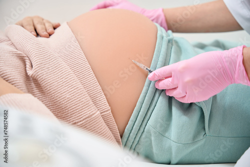Close-up woman general practitioner making injection to pregnant woman