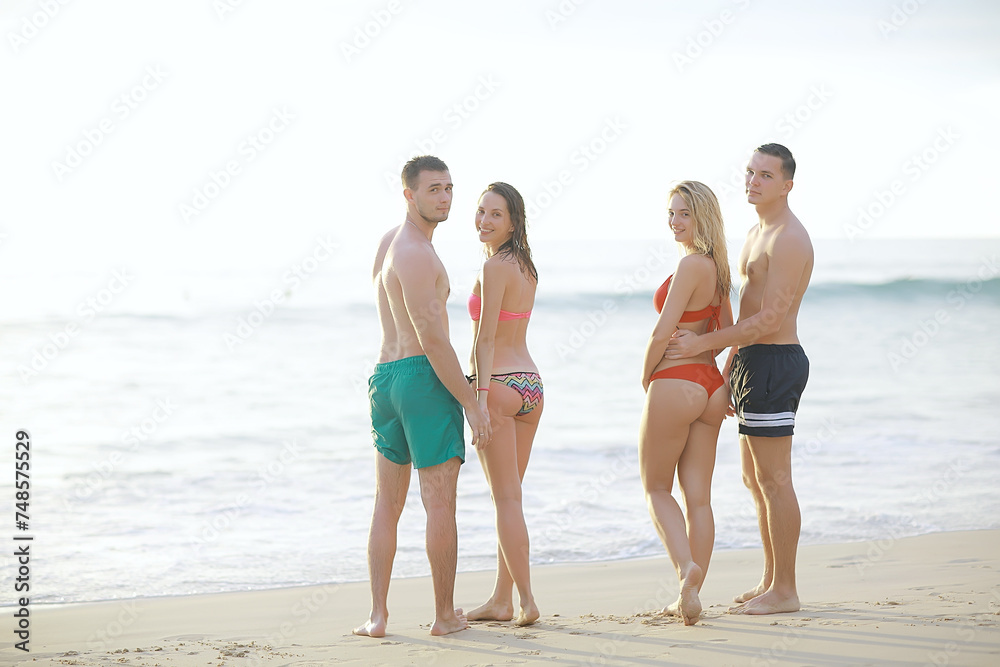 group of happy friends relaxing by the sea
