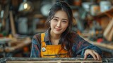 Young female Asian carpenter working in carpentry work place,carpenter woman measuring wood plank on work bench,smiling carpenter concentrate with handicraft wood working, 