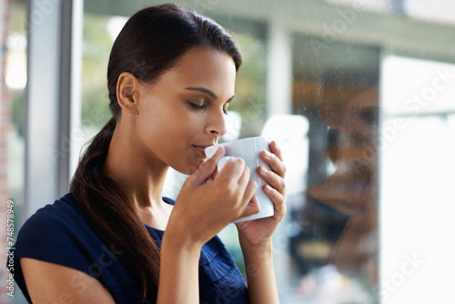 Woman, relax and drinking coffee in home for peace, calm and energy at breakfast in the morning. Matcha, tea cup and young person with espresso, latte or hot healthy beverage for wellness by window photo