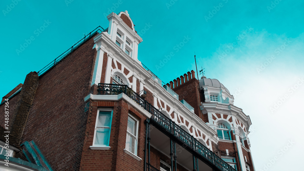 The photo showcases an English building against a vivid azure sky, embodying the charm of traditional architecture set against nature's brilliant canvas The photo showcases an English building against a vivid azure sky, embodying the charm of traditional architecture set against nature's brilliant canvas