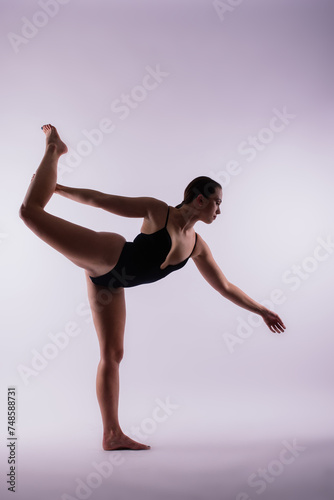 Young beautiful female yoga posing on a gray studio background