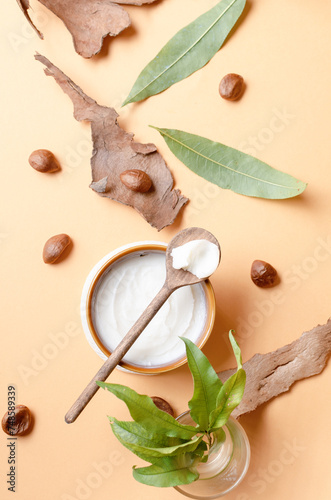 top view of Shea butter in a beige bowl on light beige background with nut and leaves. Product moisturizer natural for beauty, cosmetics and spa. photo