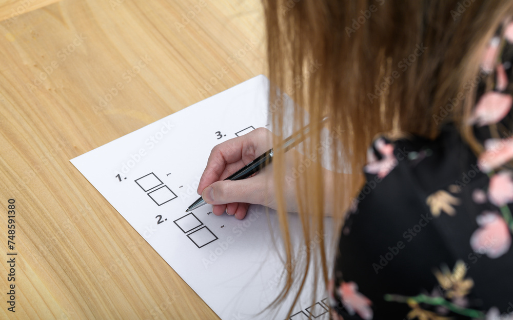 Dziewczyna wypełnia test, zaznacza długopisem odpowiedzi - obrazy, fototapety, plakaty 