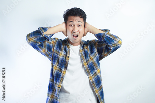 Adult Asian man screaming desperate while close his ears with hand photo
