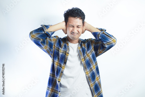 Adult Asian man screaming desperate while close his ears with hand photo