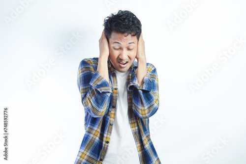 Adult Asian man screaming desperate while close his ears with hand photo