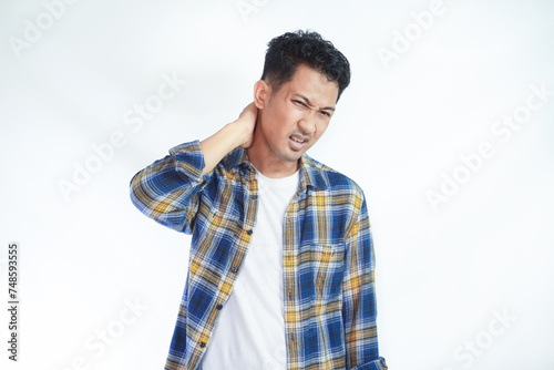 Adult Asian man touching back of his neck with pain expression photo
