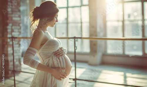 Pregnant woman posing near barre in ballet studio