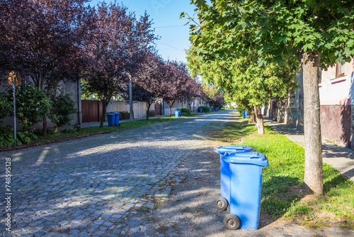 Blue garbage cans on the street in a small town near every house. Centralized garbage collection in a small cozy European city. Garbage collection on a certain day of the week. photo