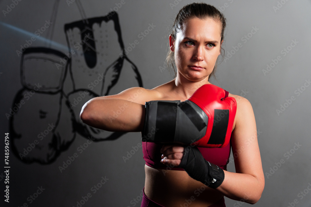 Portrait of an athletic woman who takes off her boxing gloves after training