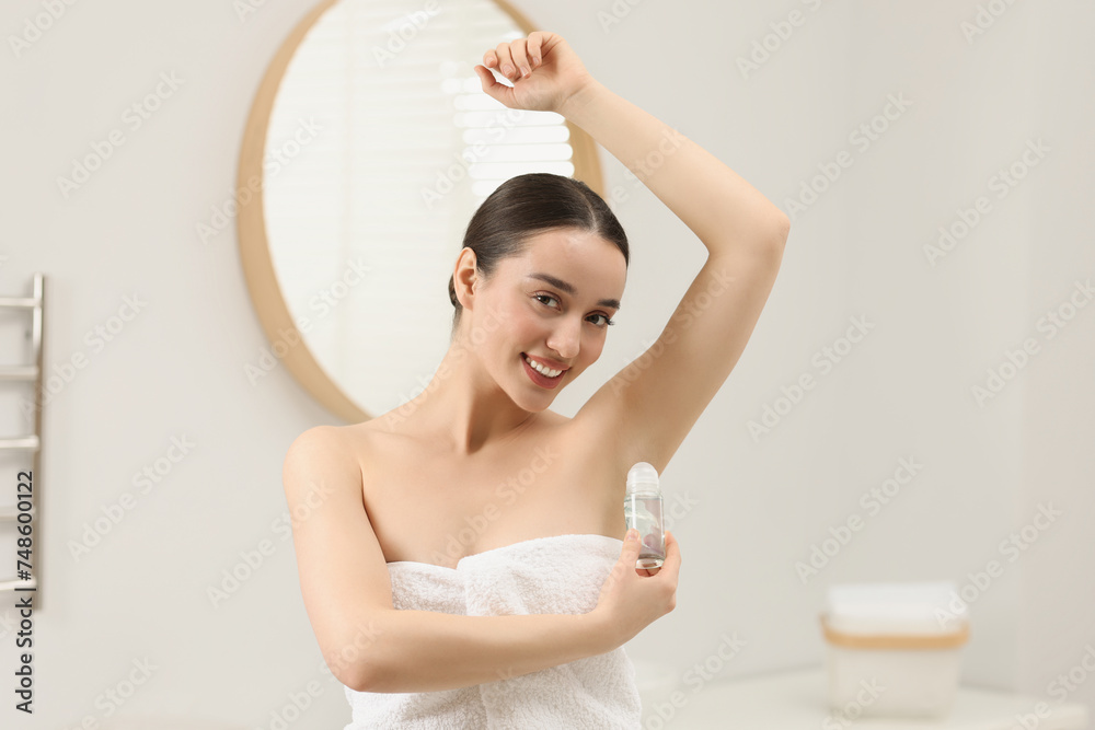 Beautiful young woman applying deodorant in bathroom Beautiful young woman applying deodorant in bathroom