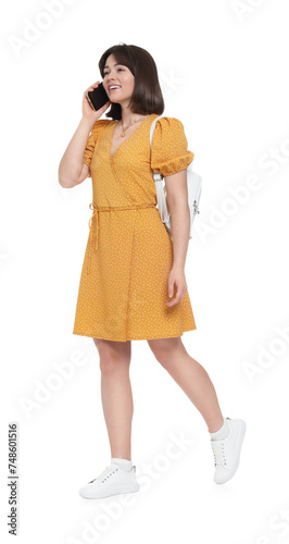 Happy woman with backpack talking on smartphone against white background © New Africa