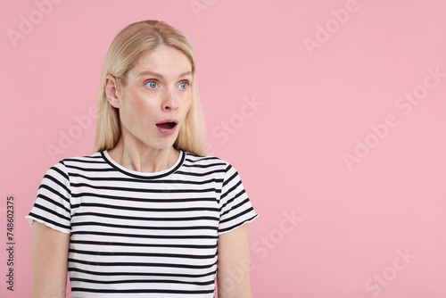 Portrait of surprised woman on pink background, space for text © New Africa