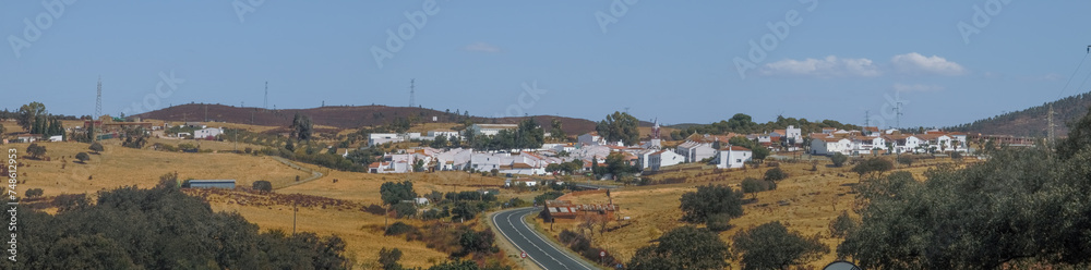 El Granado, pequeño pueblo de casas encaladas en el suroeste de España. Pueblo ubicado en un valle rodeado de colinas. Vista panorámica desde el sur donde llega una carretera asfaltada.