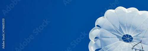 White parachute against a blue sky banner. photo