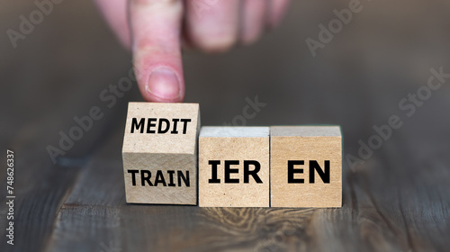 Wooden cubes show the German words 'meditieren' (meditation) and 'traimieren' (train). Symbol for the balance of mind and body.