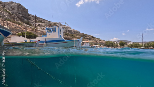 Underwater split photo of traditional fishing wooden boats in port of Iraklia island, small Cyclades, Greece