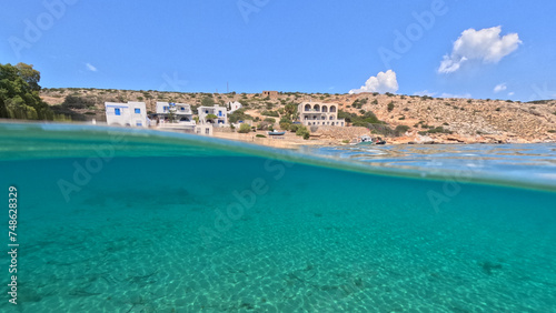 Underwater split photo of paradise crystal clear sea beach of Agios Georgios in main port of Irakleia island covered in Armirikia trees providing natural shade, small Cyclades, Greece © aerial-drone