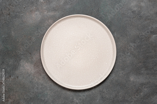 Empty beige plate on a dark grunge background. Top view, flat lay, copy space.