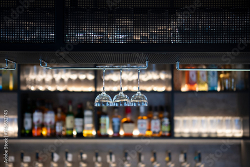 Upside Down Glassware Suspended Over a Bar Counter in Dim Lighting