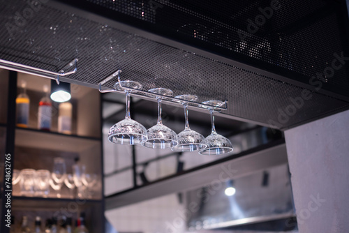 Upside Down Glassware Suspended Over a Bar Counter in Dim Lighting
