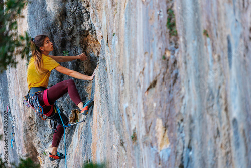 The girl climbs the rock. The climber trains on natural terrain. Extreme sport. A woman overcomes a difficult route rock climbing..