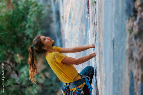 The girl climbs the rock. The climber trains on natural terrain. Extreme sport. A woman overcomes a difficult route rock climbing..