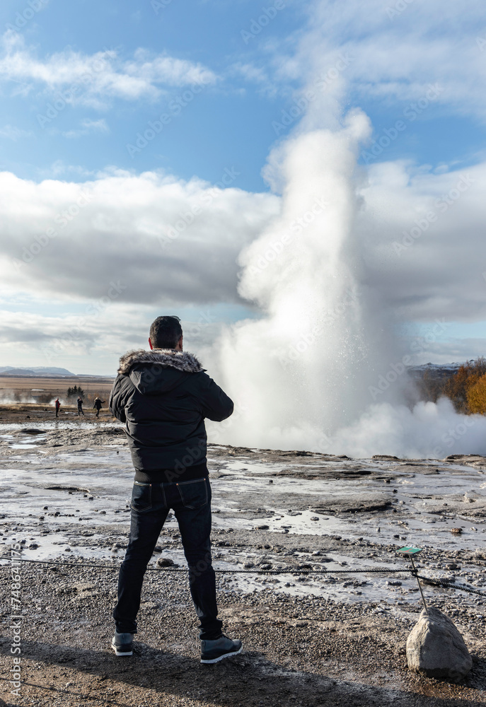Unrecognizable traveler standing near steaming geyser