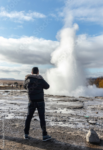 Unrecognizable traveler standing near steaming geyser